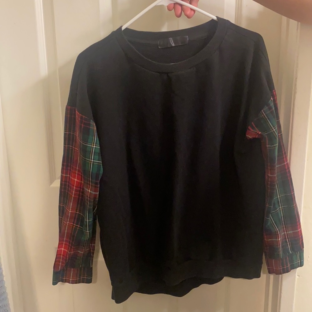 A black crew neck sweater with a square print in the arms. Warm but not too warm